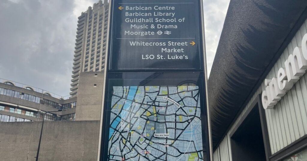 London travel zones explained featuring You Are Here street sign outside Moorgate station showing Barbican Centre on left and Whitecross Street on right