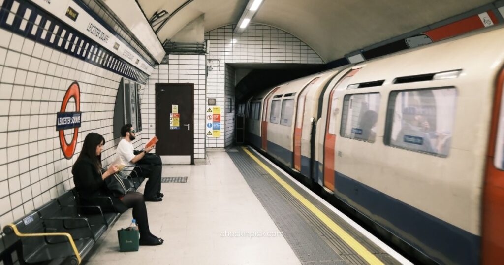London travel tips for public transport showing London Underground Tube train arriving at station with two passengers waiting on platform bench